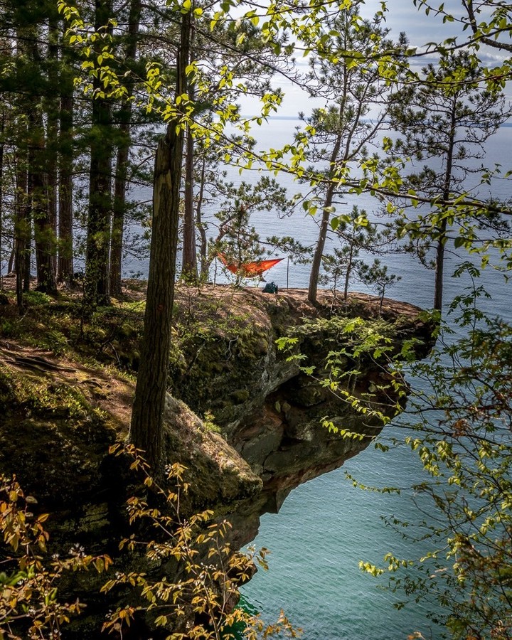 An amazing Apostle Islands photo with a person relaxing in a hammock, perilously close to a cliff that juts out over Lake Superior.