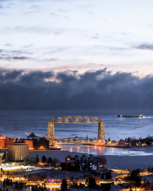 Aerial lift bridge in Duluth, MN at dusk with thick clouds on the horizon.