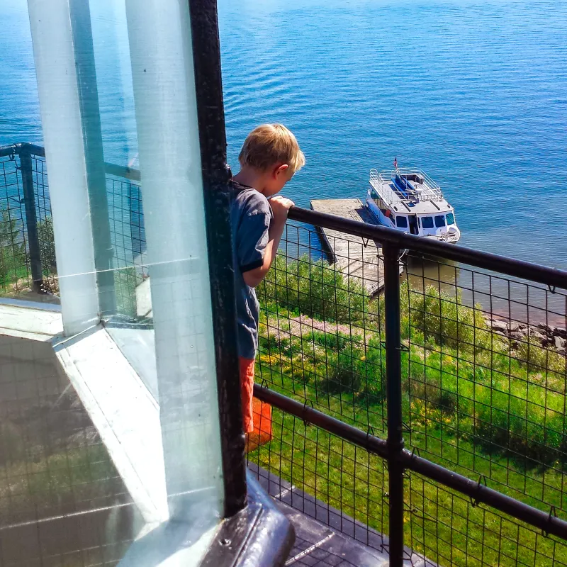 A child peers over the edge on the top of the Raspberry Island Lighthouse Tower