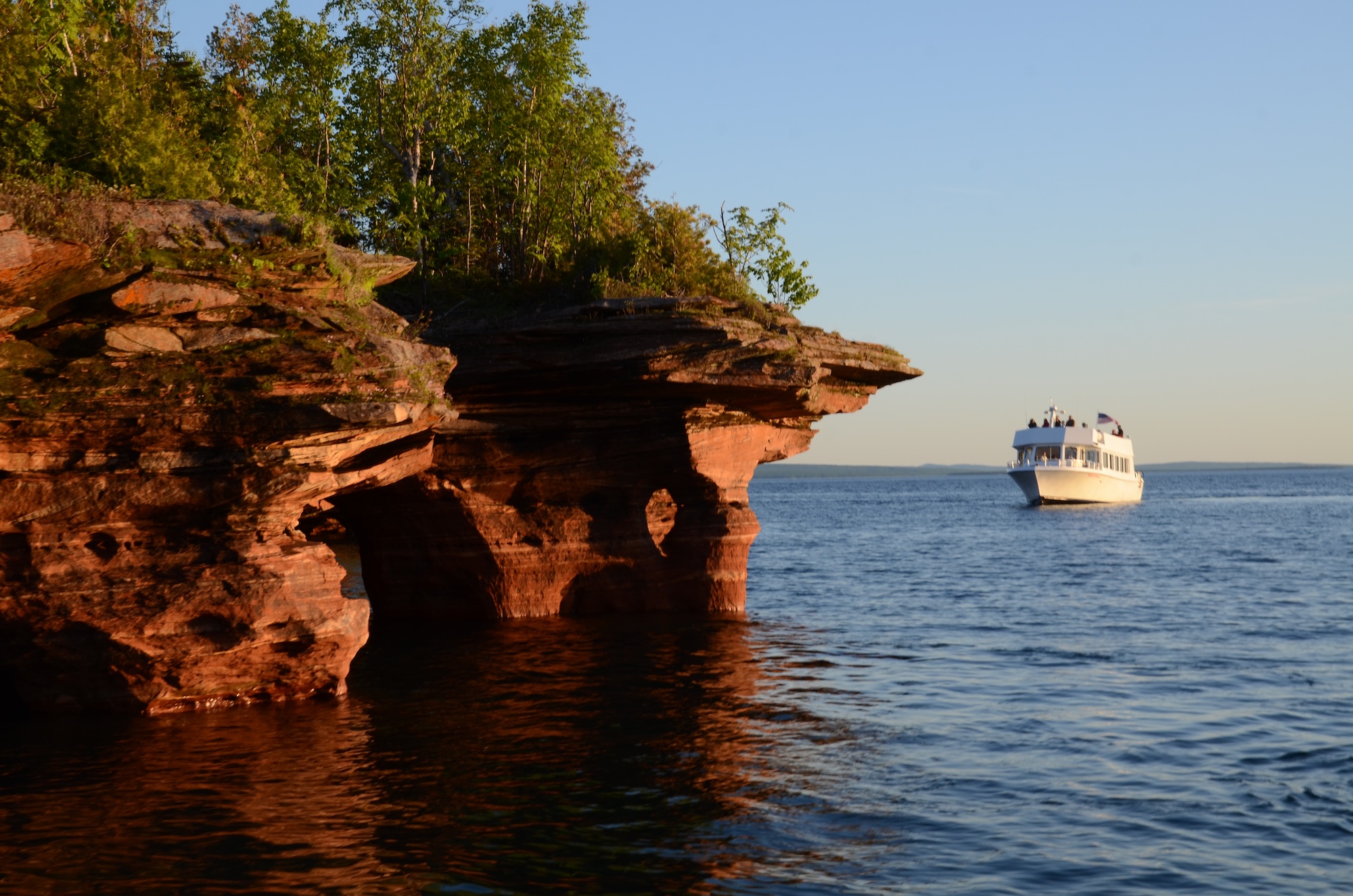 A baby deer is tucked up next to a log in Apostle Islands, Wisconsin's Crown Jewels.